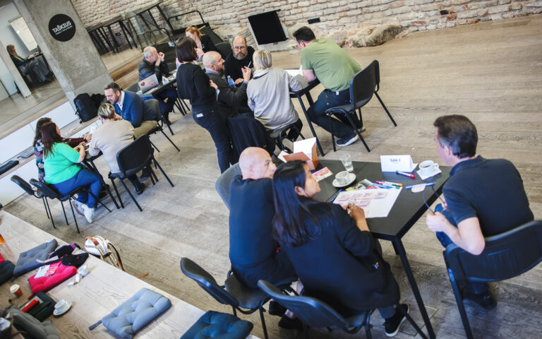 Workshop-Runde an Tischen in einer Backsteinhalle beim Engagement-Treffen