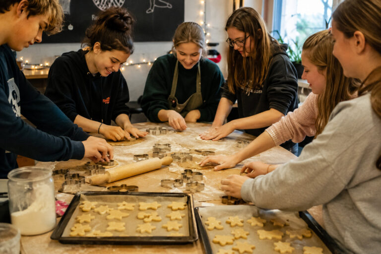 Jugendliche rollen Teig aus und backen gemeinsam Plätzchen