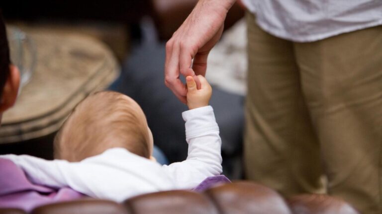 Baby liegt auf einer Decke, Erwachsene musizieren mit Trommeln