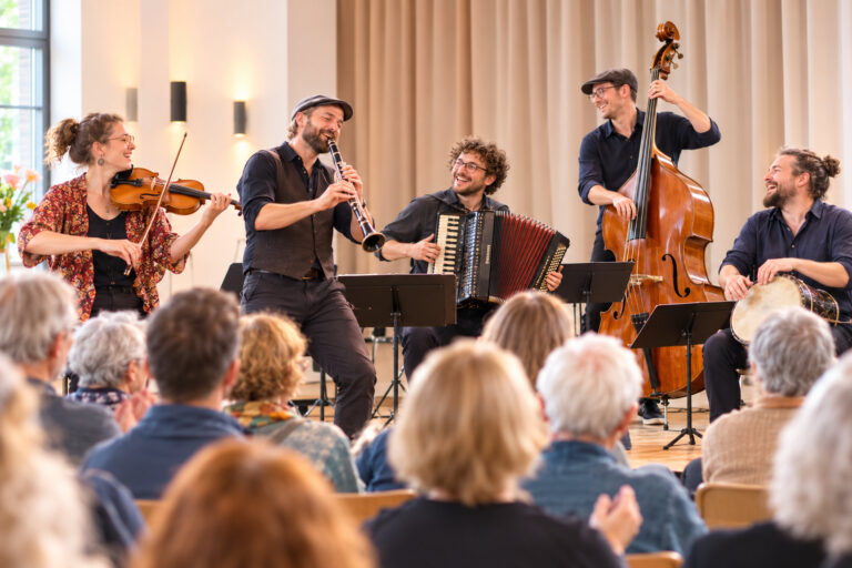 Musikensemble mit Geige, Klarinette und Kontrabass spielt vor Publikum